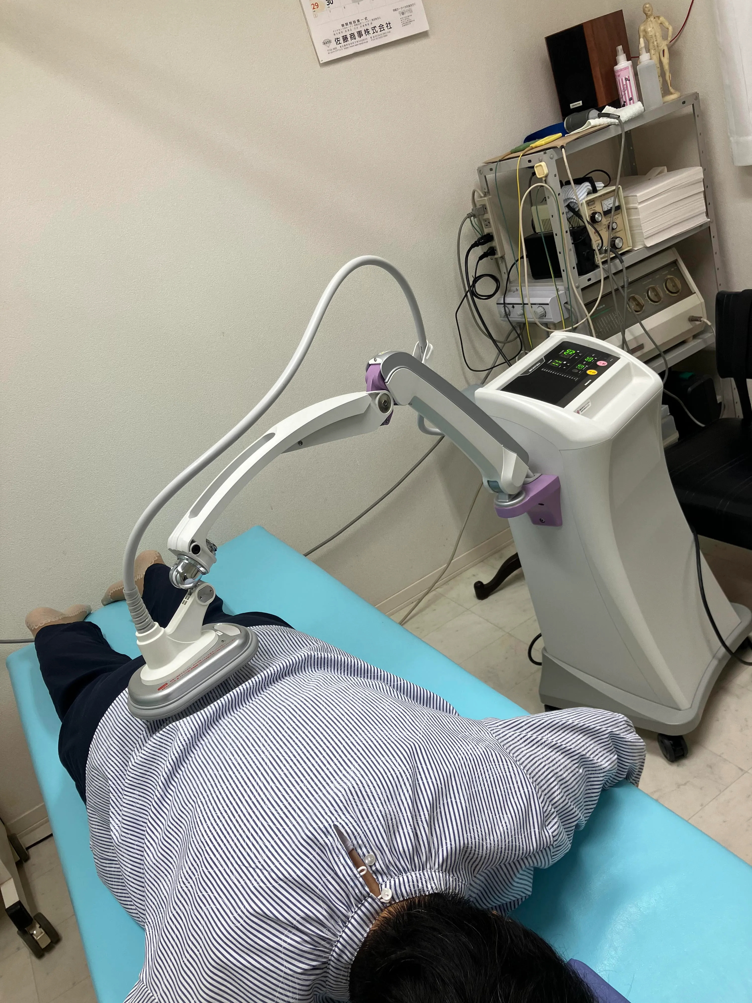 写真：大人の背中に機械を使って電気をあてています。