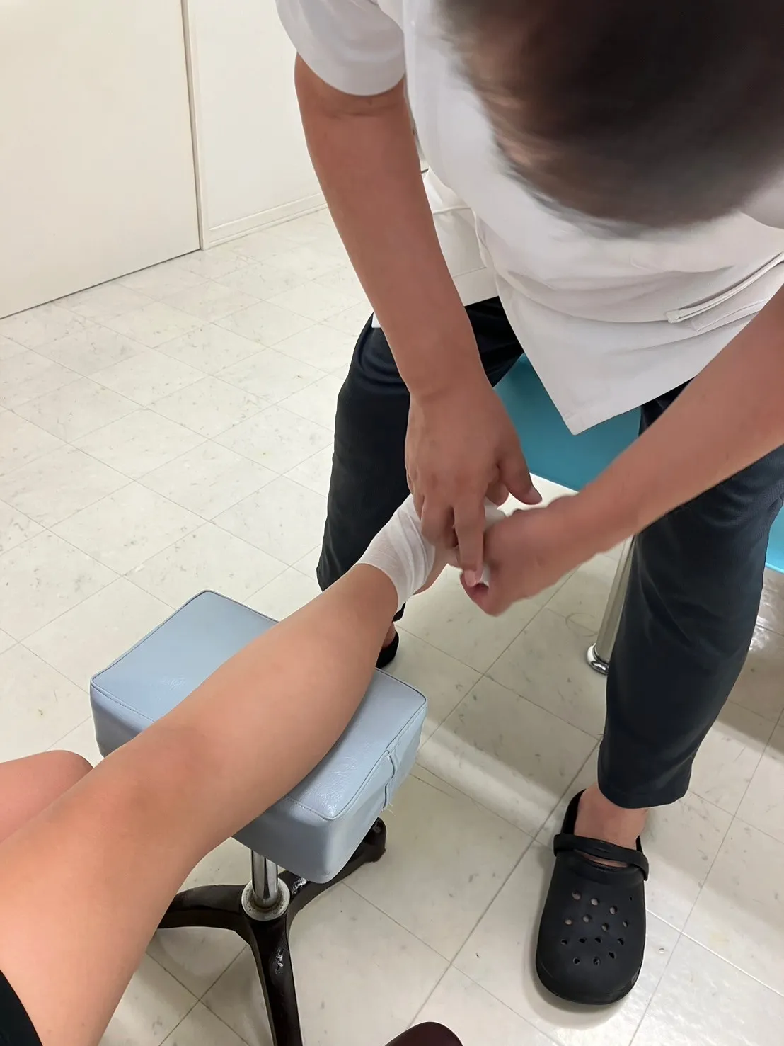 写真：子供の足に包帯を巻いています。