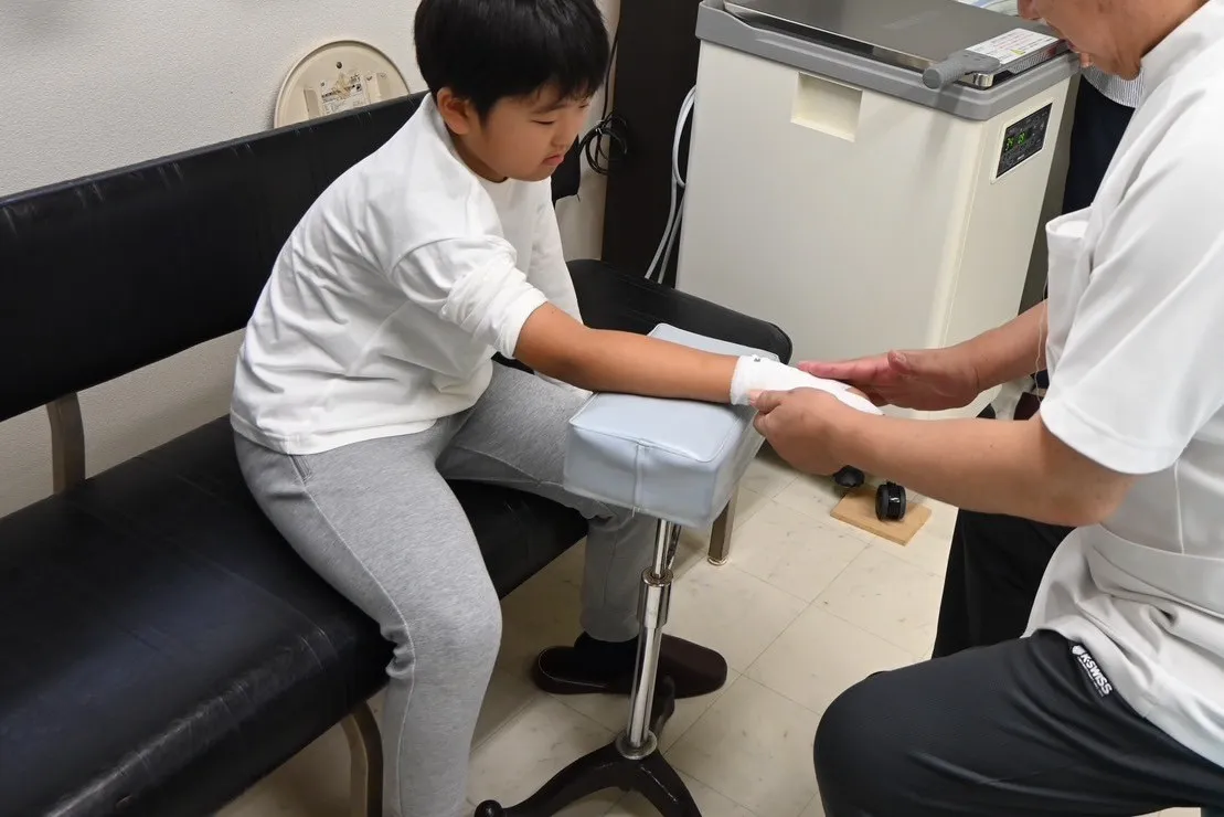 写真：子供の手に包帯を巻いています。