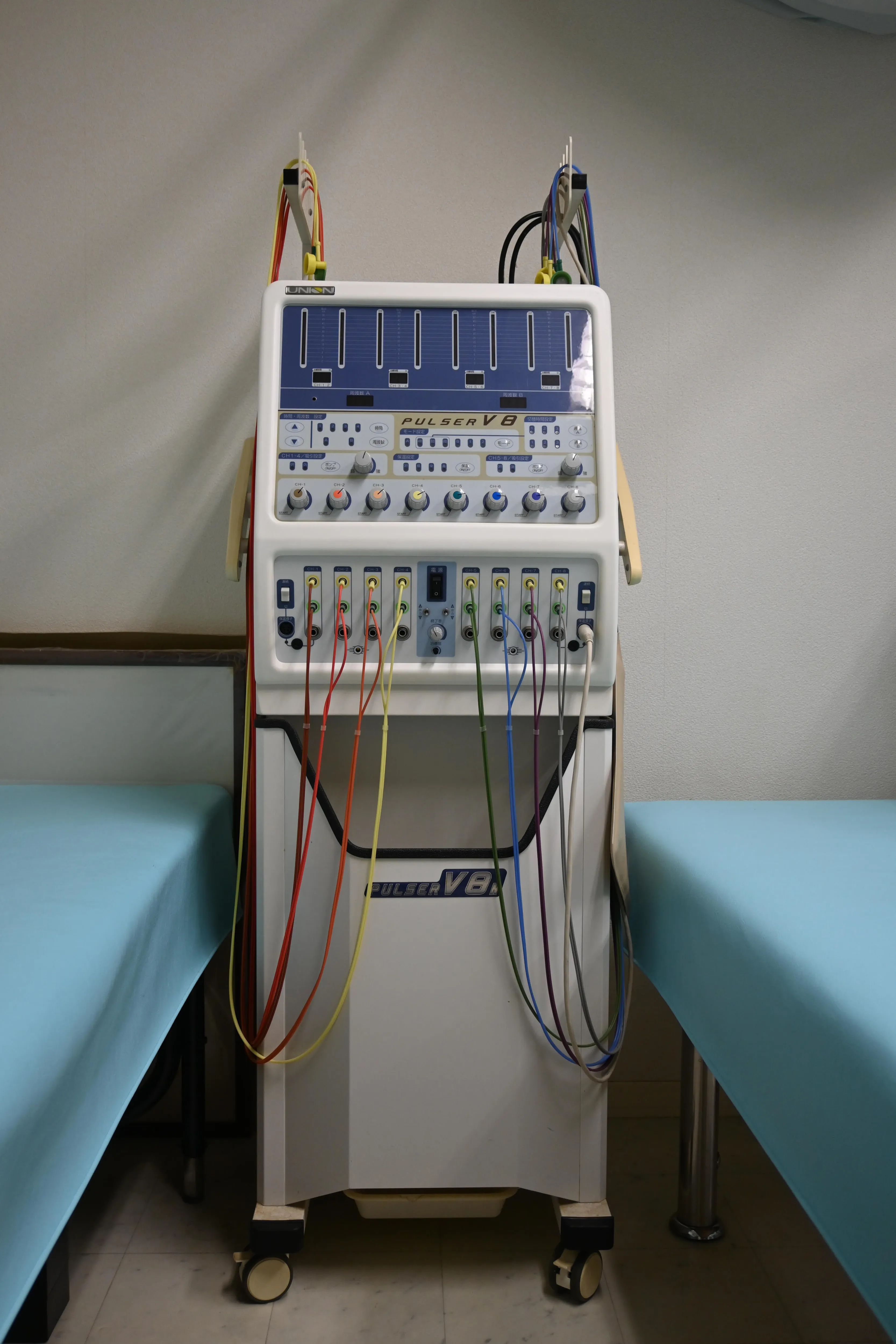 写真：機械。ベッドの合間に置いてあります。沢山のボタンととコードがついています。