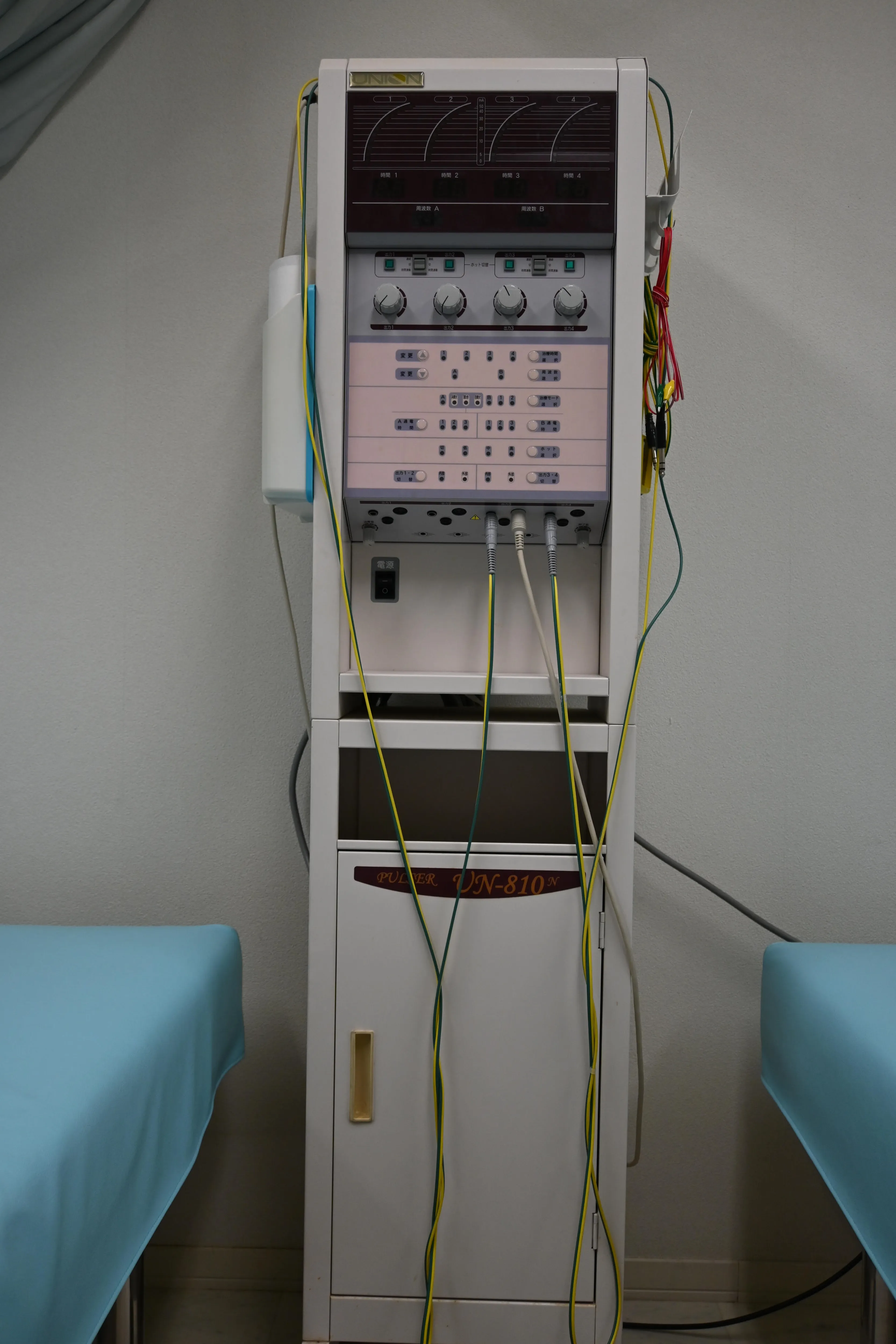 写真：機械。ベッドの合間に置いてあります。沢山のボタンととコードがついています。