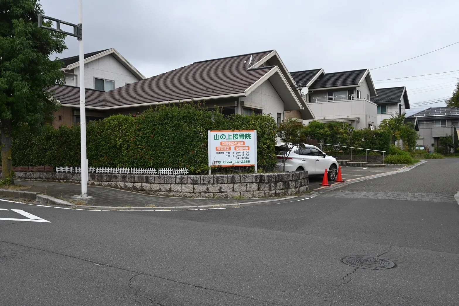 写真：外観。道路に面した一軒家と看板が見えます。