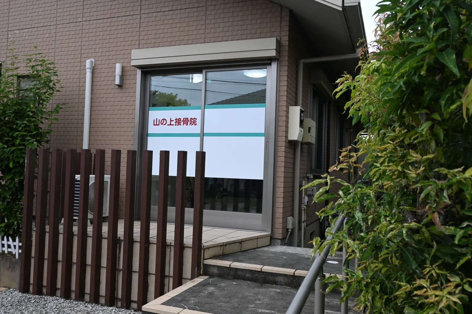 写真：外観。窓のように見える大きなガラス扉に山の上接骨院と書いてあります。